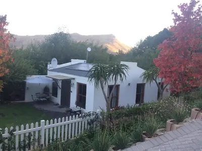 a white house with a white fence and trees at Swan Cottage in Kylemore