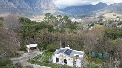 a white house on a hill with mountains in the background at Swan Cottage in Kylemore