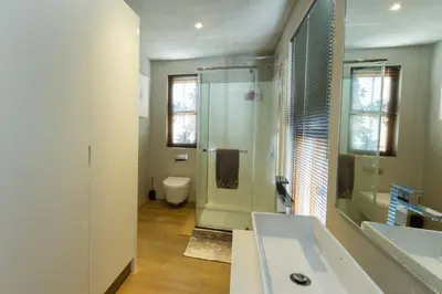 a bathroom with a shower and two sinks and a toilet at Swan Cottage in Kylemore