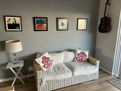a living room with a couch with pillows and a guitar at Silversands Serenity in Bettyʼs Bay