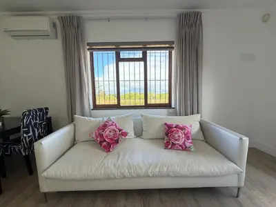 a white couch with pink pillows in a living room at Plattekloof Mountain view in Plattekloof