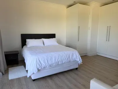 a bedroom with a bed with white sheets and white cabinets at Plattekloof Mountain view in Plattekloof