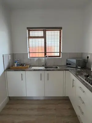a kitchen with white cabinets and a sink and a window at Plattekloof Mountain view in Plattekloof