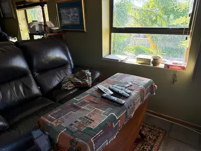 a living room with a couch and a table with remote controls at Balcony mountain views free fibre-wifi aircon and parking in Wellington