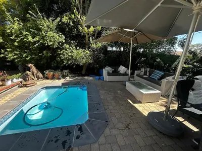 a swimming pool with an umbrella and a chair and a couch at Dove Cottage in Oakdale