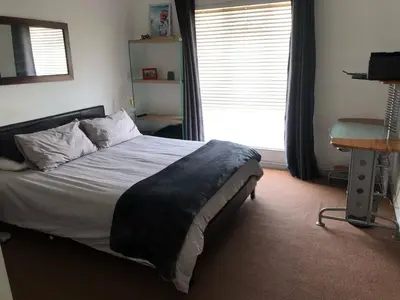 a bedroom with a bed and a window and a desk at Central and close to the beach in Cape Town