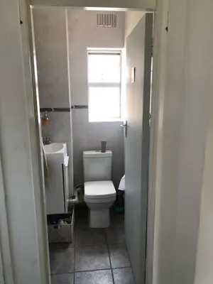 a small bathroom with a toilet and a window at Central and close to the beach in Cape Town
