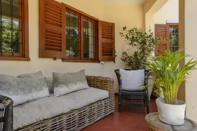a wicker couch in a living room with windows at Am Flus- at the river in Stellenbosch
