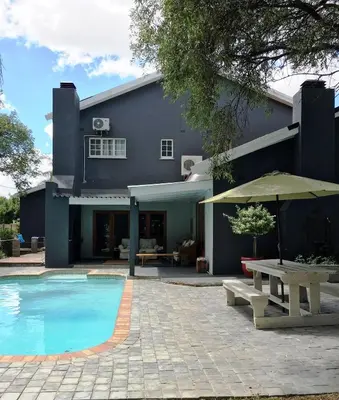 a house with a swimming pool and a table and umbrella at The Garden Shed Guest House in Wellington