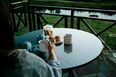 a person sitting at a table with cups of coffee and pastries at MontMartre Chalets & Venue in Franschhoek