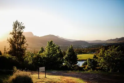 a sign on a hill with trees and a lake at MontMartre Chalets & Venue in Franschhoek