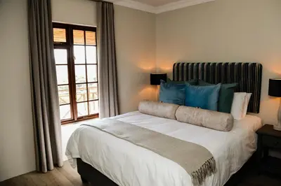 a bedroom with a large bed with blue pillows at MontMartre Chalets & Venue in Franschhoek