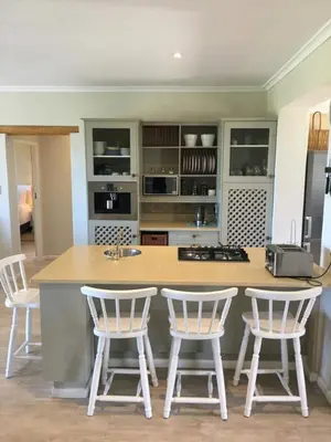 a kitchen with a island with four bar stools at Sea front holiday home in Bettyʼs Bay