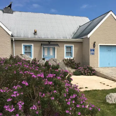 a house with purple flowers in front of it at Sea front holiday home in Bettyʼs Bay