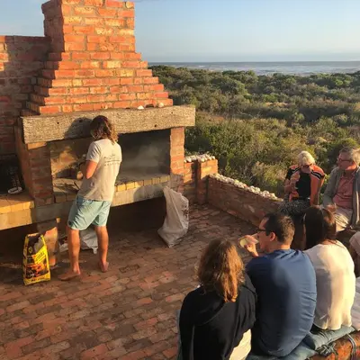 a group of people sitting around a brick oven at Sea front holiday home in Bettyʼs Bay