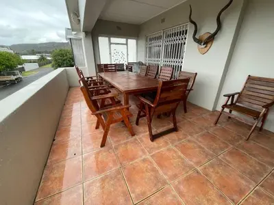a porch with a wooden table and chairs on a balcony at Salty Leaves in Hermanus
