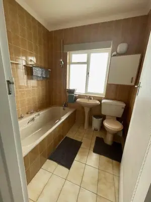 a bathroom with a tub and a toilet and a sink at Salty Leaves in Hermanus