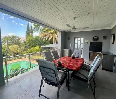a dining room with a table and chairs on a balcony at Paarl View House in Paarl