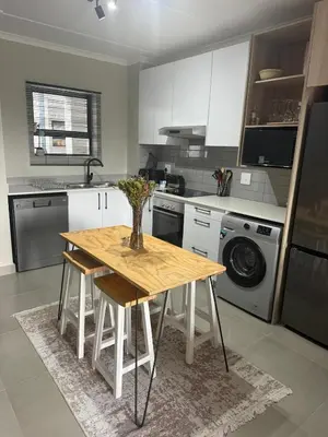 a kitchen with a wooden table with a vase on it at Modern stay overlooking Durbanville wine country in Durbanville