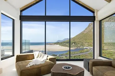a living room with large windows and a couch and a table at Nowhere Els in Rooiels