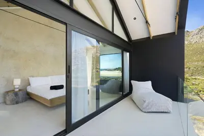 a room with glass doors and a bed and a window at Nowhere Els in Rooiels
