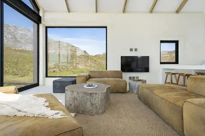 a living room with a couch and a table and a tv at Nowhere Els in Rooiels