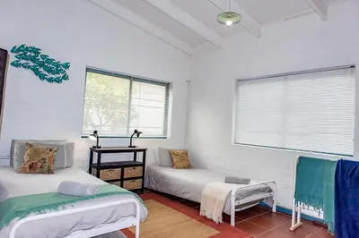 a room with two beds and a couch and windows at Bagatelle in Pringle Bay