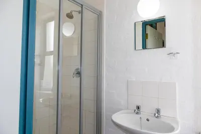 a white bathroom with a sink and a shower at Bagatelle in Pringle Bay