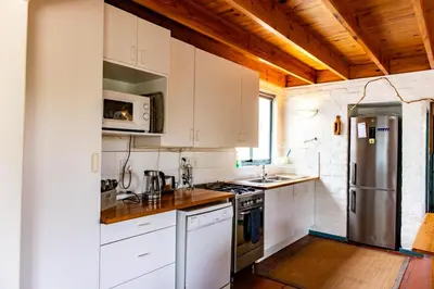a kitchen with white cabinets and a stainless steel refrigerator at Bagatelle in Pringle Bay