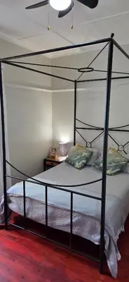 a bedroom with a metal canopy bed in a room at Bot River Farm Cottage in Botrivier