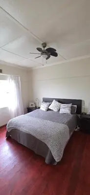 a bedroom with a bed with a ceiling fan at Bot River Farm Cottage in Botrivier