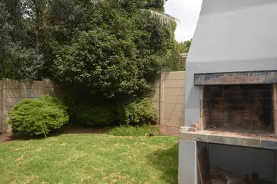 an outdoor fireplace in a yard next to a fence at 2-Bedroom Private Garden Flat, Durbanville in Durbanville