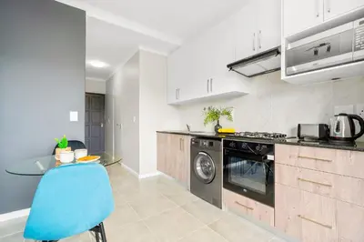 a kitchen with a table and a blue chair at The Orion 16 in Table View