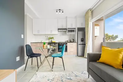 a kitchen and a living room with a table and chairs at The Orion 16 in Table View