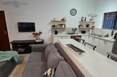 a living room with a couch and a kitchen at Bed and Biscuits in Windmeul
