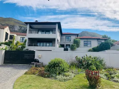 a white house with a fence and a yard at Chasing Sunsets sea and mountain views in Hermanus