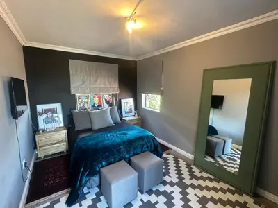 a bedroom with a bed and a large mirror at Chasing Sunsets sea and mountain views in Hermanus
