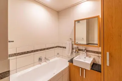 a bathroom with a bath tub and a sink at Ezey Tours-Manhattan Suites in Cape Town