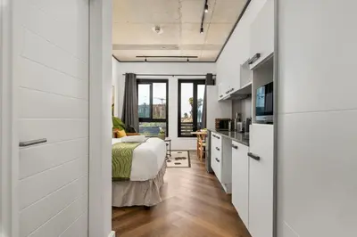 a bedroom with a bed and a kitchen at Bridgewater One 206 in Cape Town