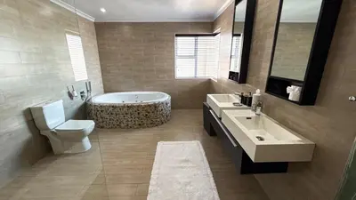 a bathroom with a tub and a toilet and a sink at The Sunset Edition in Cape Town