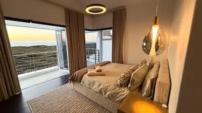 a bedroom with a bed with a view of the ocean at The Sunset Edition in Cape Town