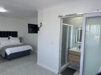 a bedroom with a bed and a bathroom with a shower at Plattekloof guest house in Tygerberg Hills