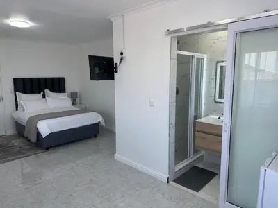 a bedroom with a bed and a walk in shower at Plattekloof guest house in Tygerberg Hills