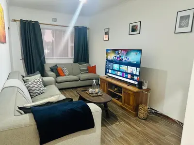 a living room with a couch and a flat screen tv at Gorgeous beachfront hideout Strand beachfront in Strand