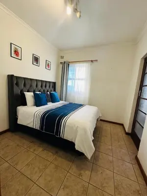 a bedroom with a large bed with blue pillows at Gorgeous beachfront hideout Strand beachfront in Strand