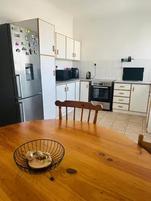 a kitchen with a wooden table and a wooden floor at Gorgeous beachfront hideout Strand beachfront in Strand