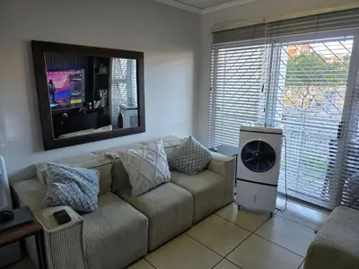 a living room with a couch and a tv at Secure 2 Bedroom Ground Floor Apartment in Joostenberg Vlakte