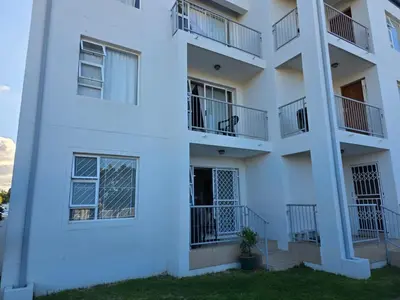 a white apartment building with balconies and a yard at Secure 2 Bedroom Ground Floor Apartment in Joostenberg Vlakte