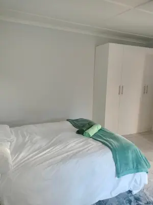 a white bed with a green blanket on top of it at Near Grandwest in Thornton