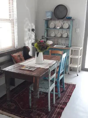 a dining room table with a vase of flowers on it at Nerf-af Cottage at Onrus, Hermanus in Hermanus